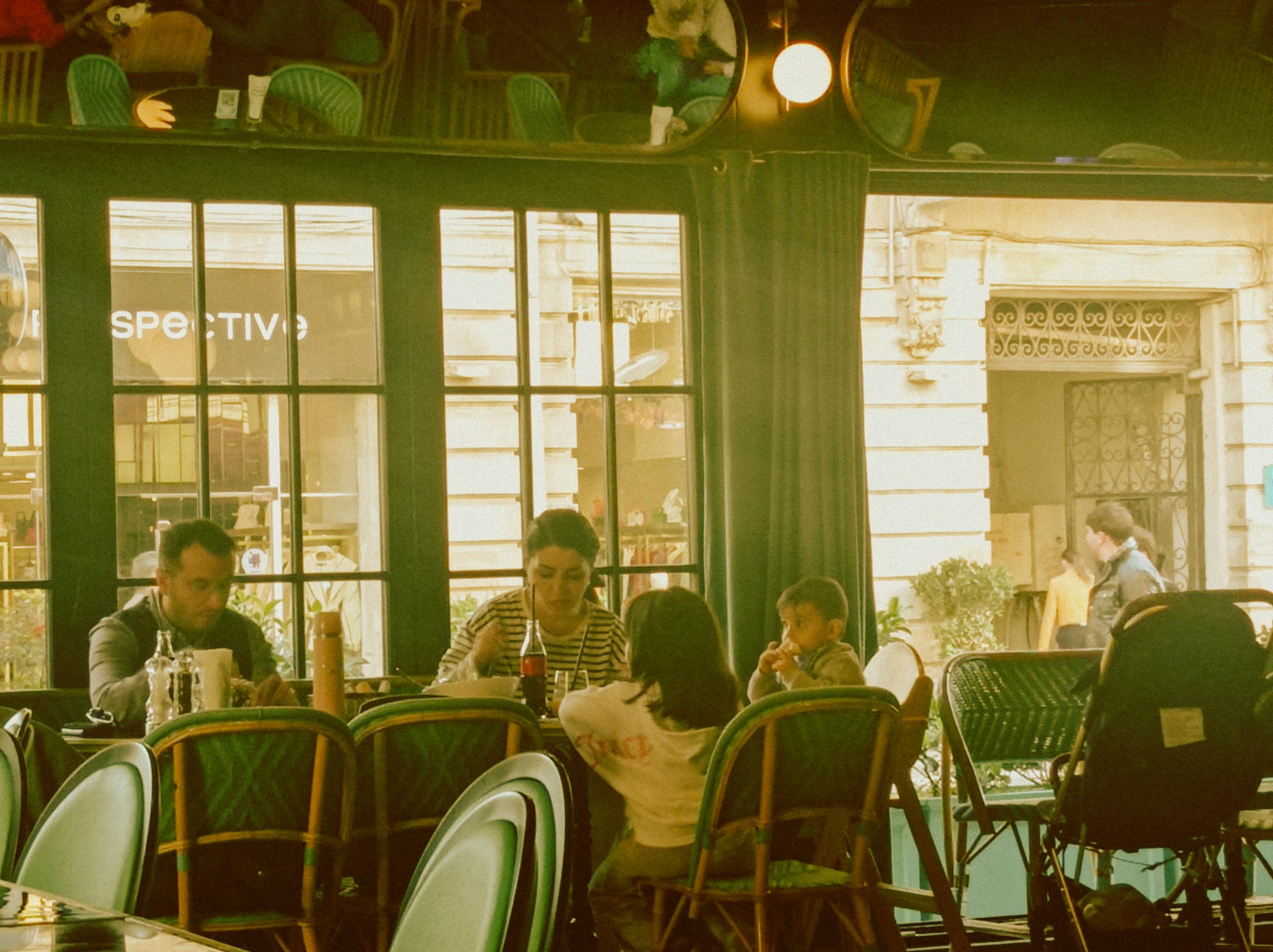 A family shares a meal in a charming cafe, enjoying quality time together.