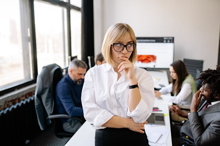 A focused businesswoman thinking during a team meeting in a modern office.