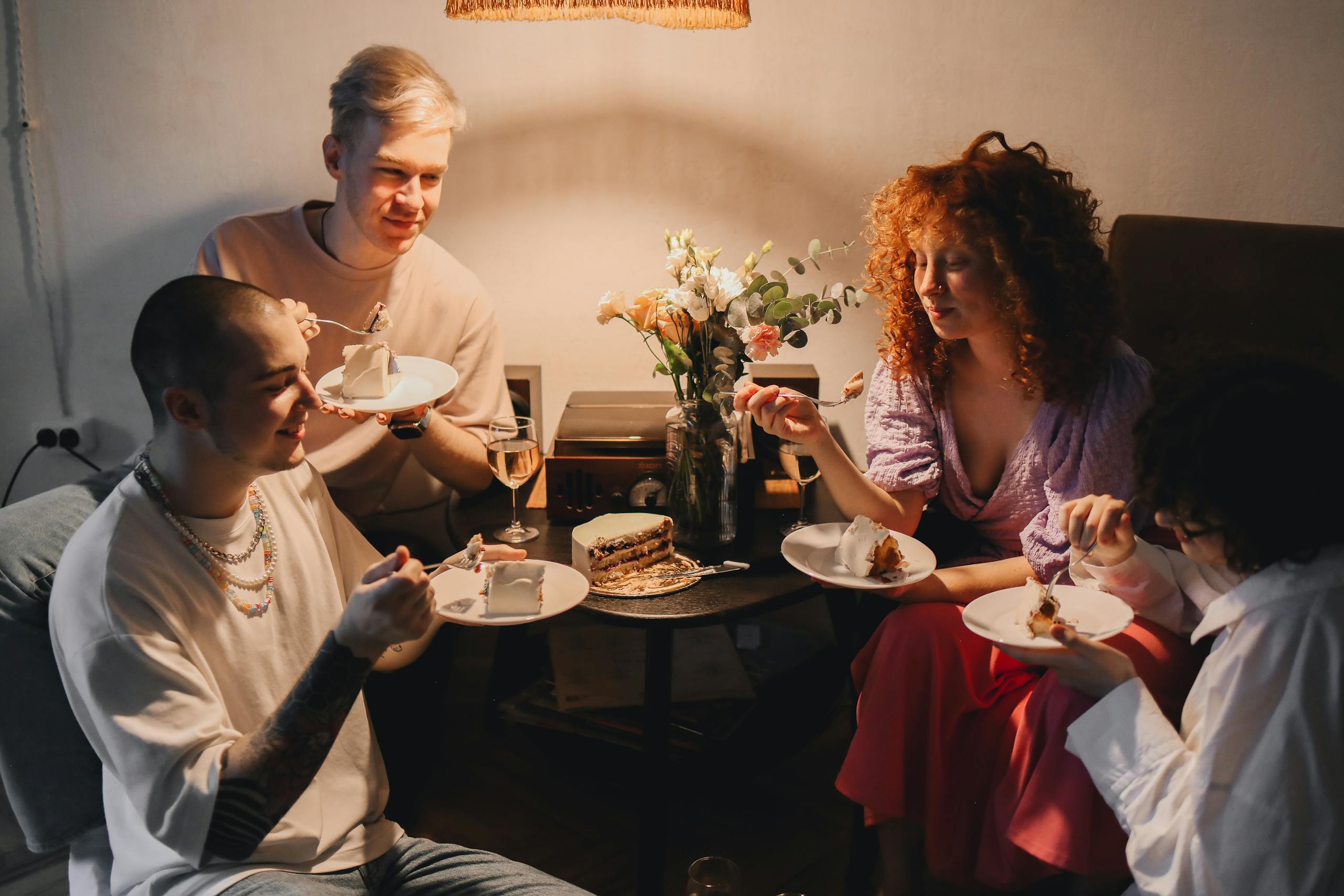 A group of friends enjoying cake and wine in a cozy indoor setting. Perfect for lifestyle themes.