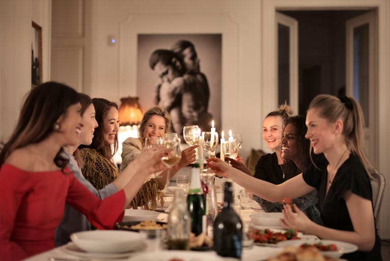 A group of women celebrating with wine at an elegant indoor dinner party, enjoying friendship and laughter.