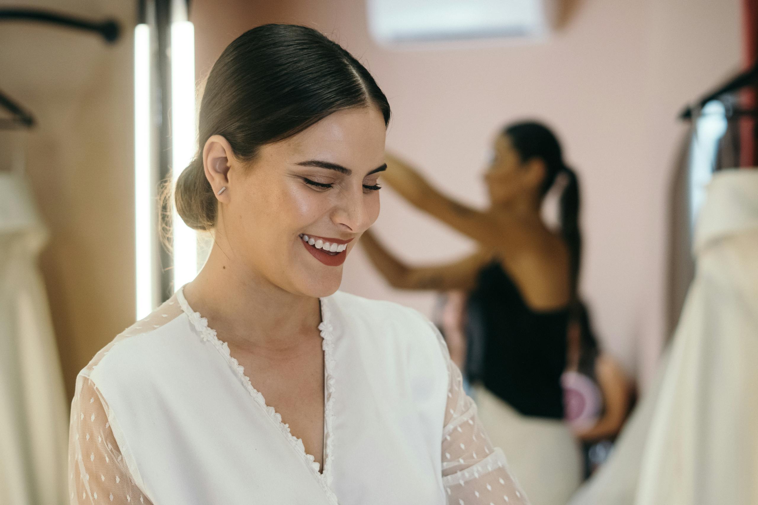 A happy bride smiles during her wedding dress fitting in a boutique.