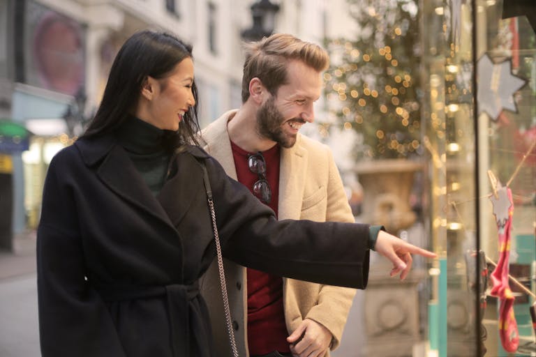 A happy couple window shopping together in an urban street setting during daylight.