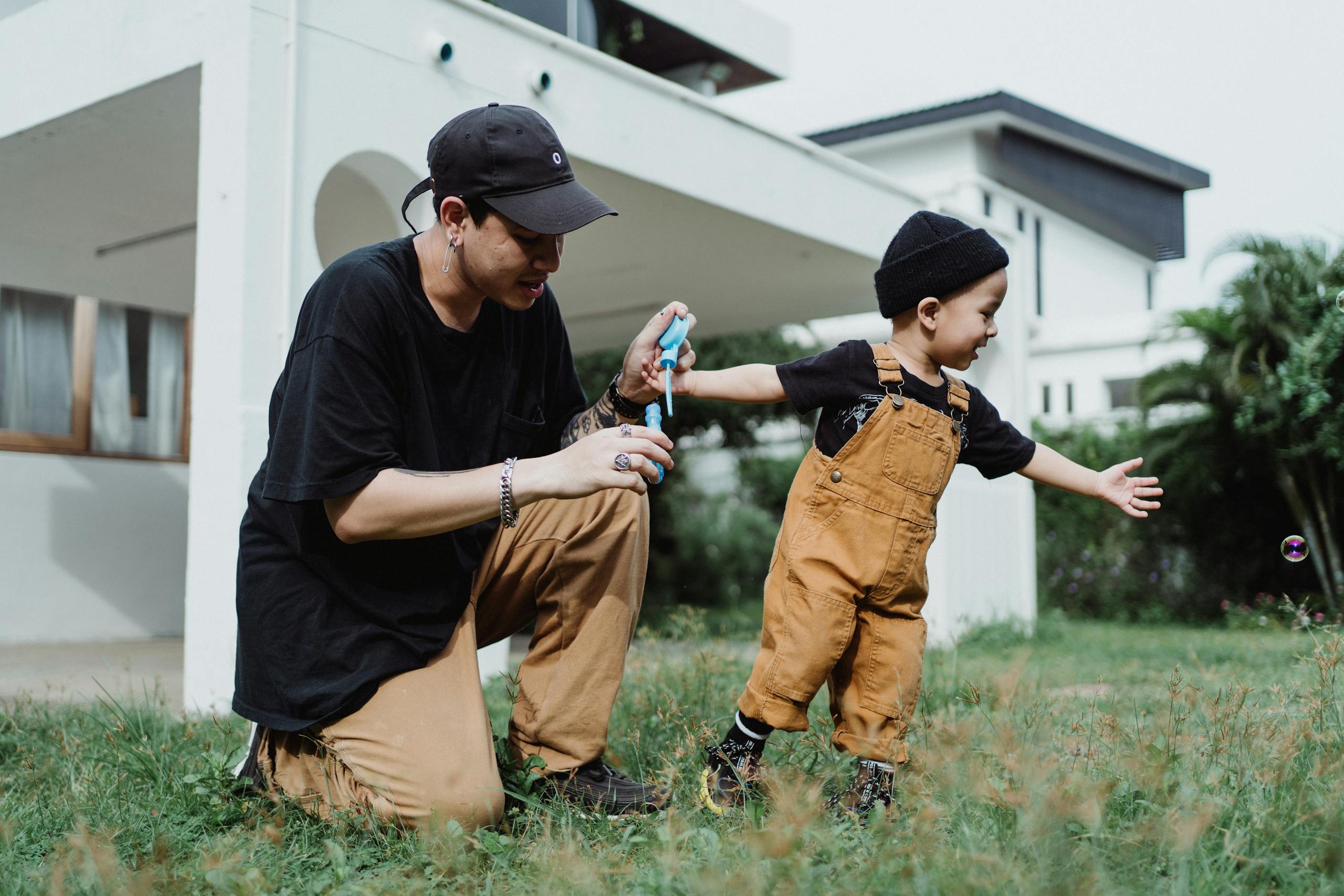 A joyful moment of a father and child playing with bubbles in a grass lawn.