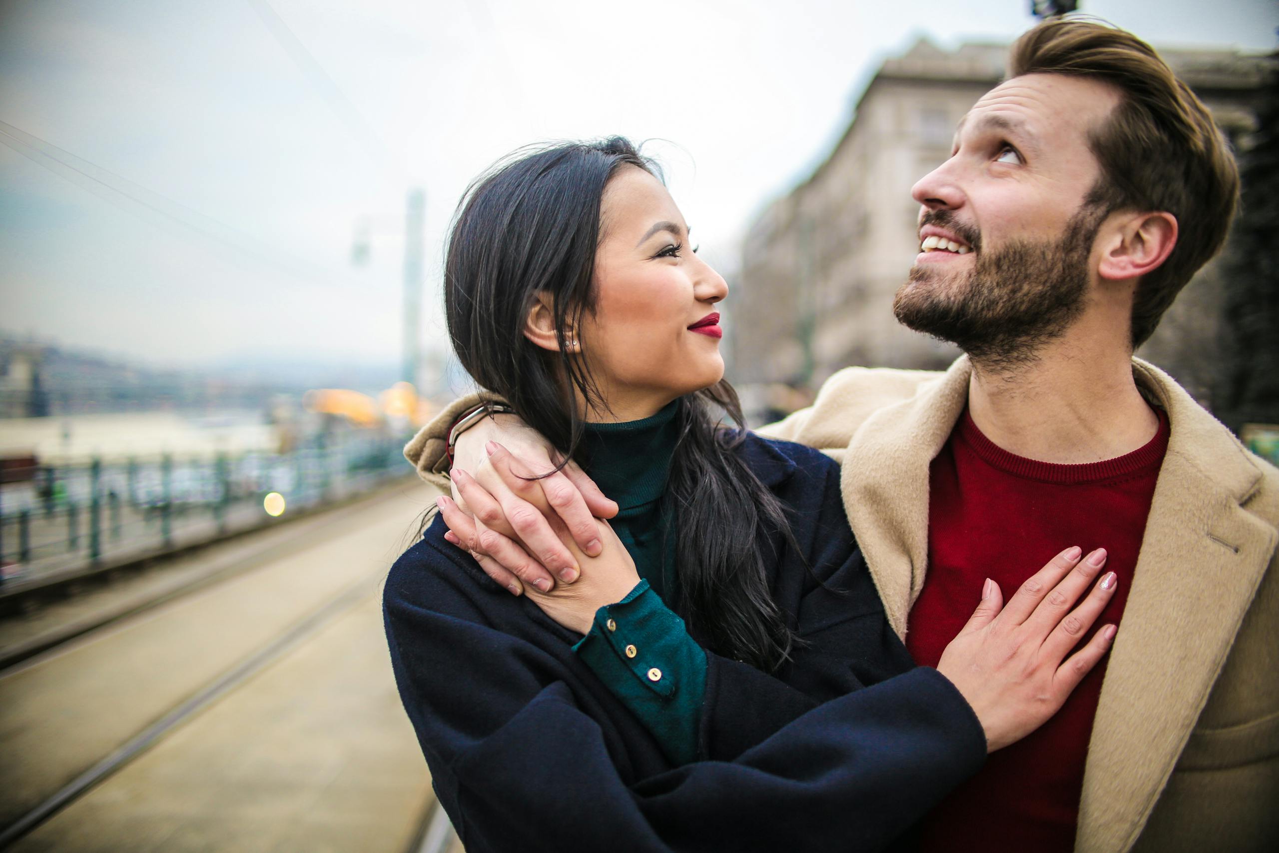 A loving couple shares a joyful embrace outdoors in a city. Perfect for romance themes.