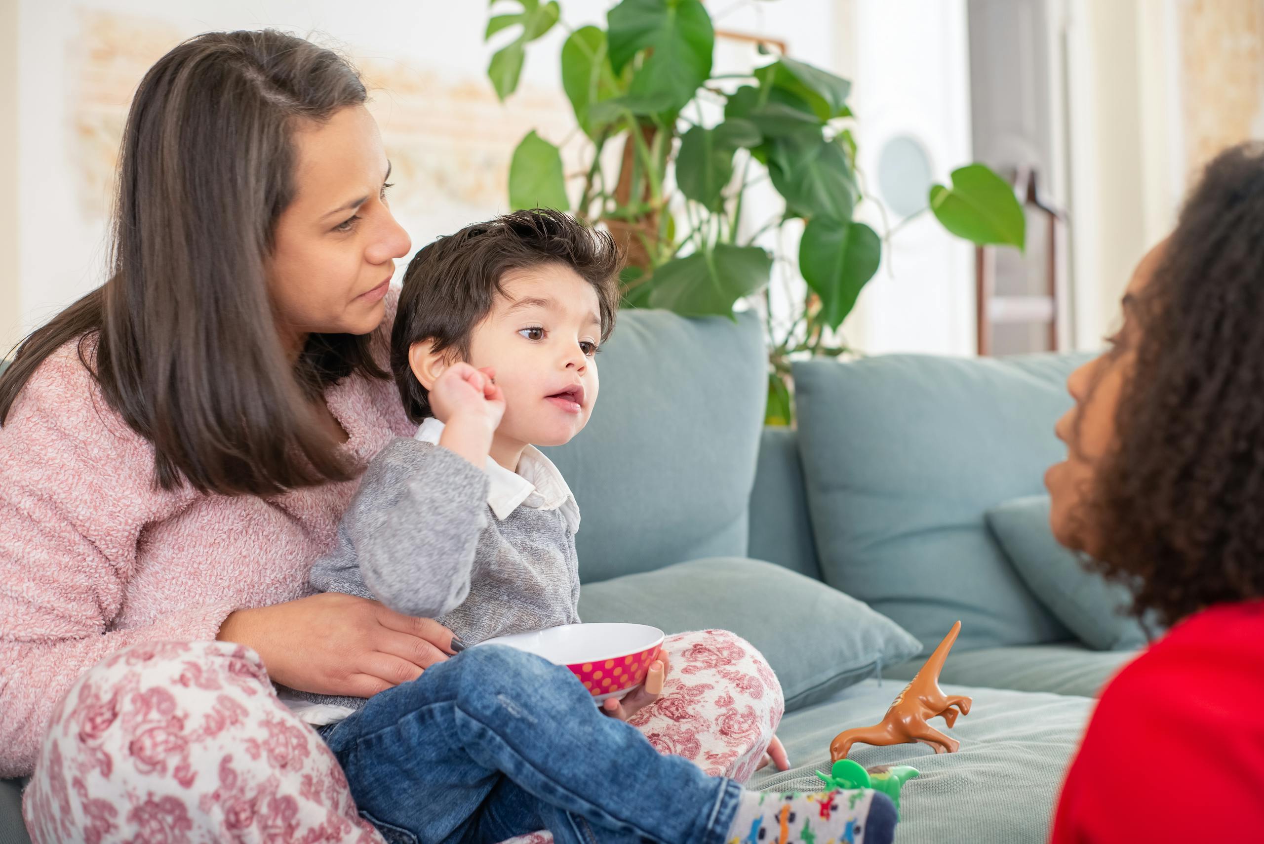 A loving family scene of diverse women and a child enjoying time together in a cozy living room.