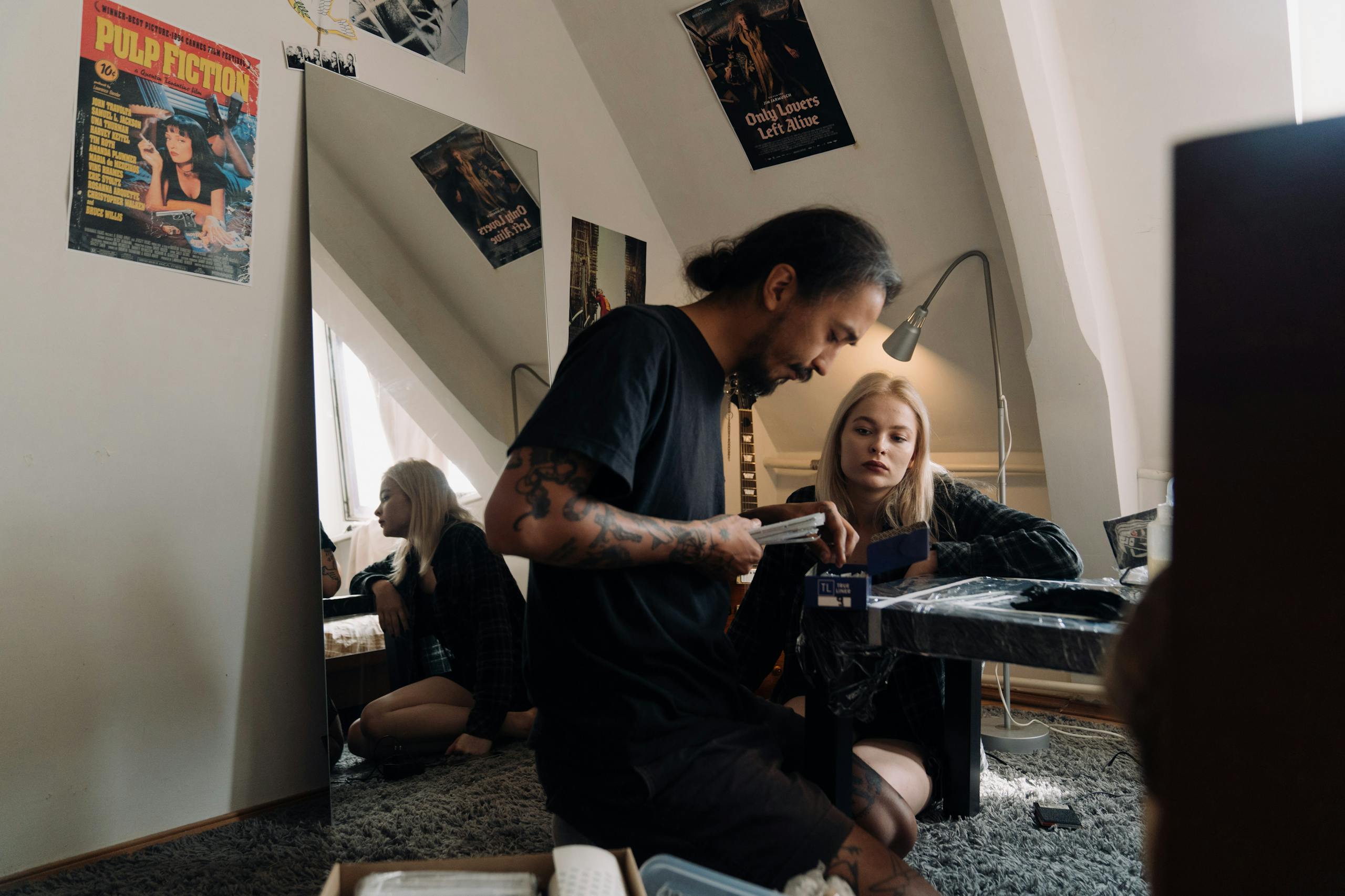 A man and woman in a stylish home interior with movie posters and creative ambiance.