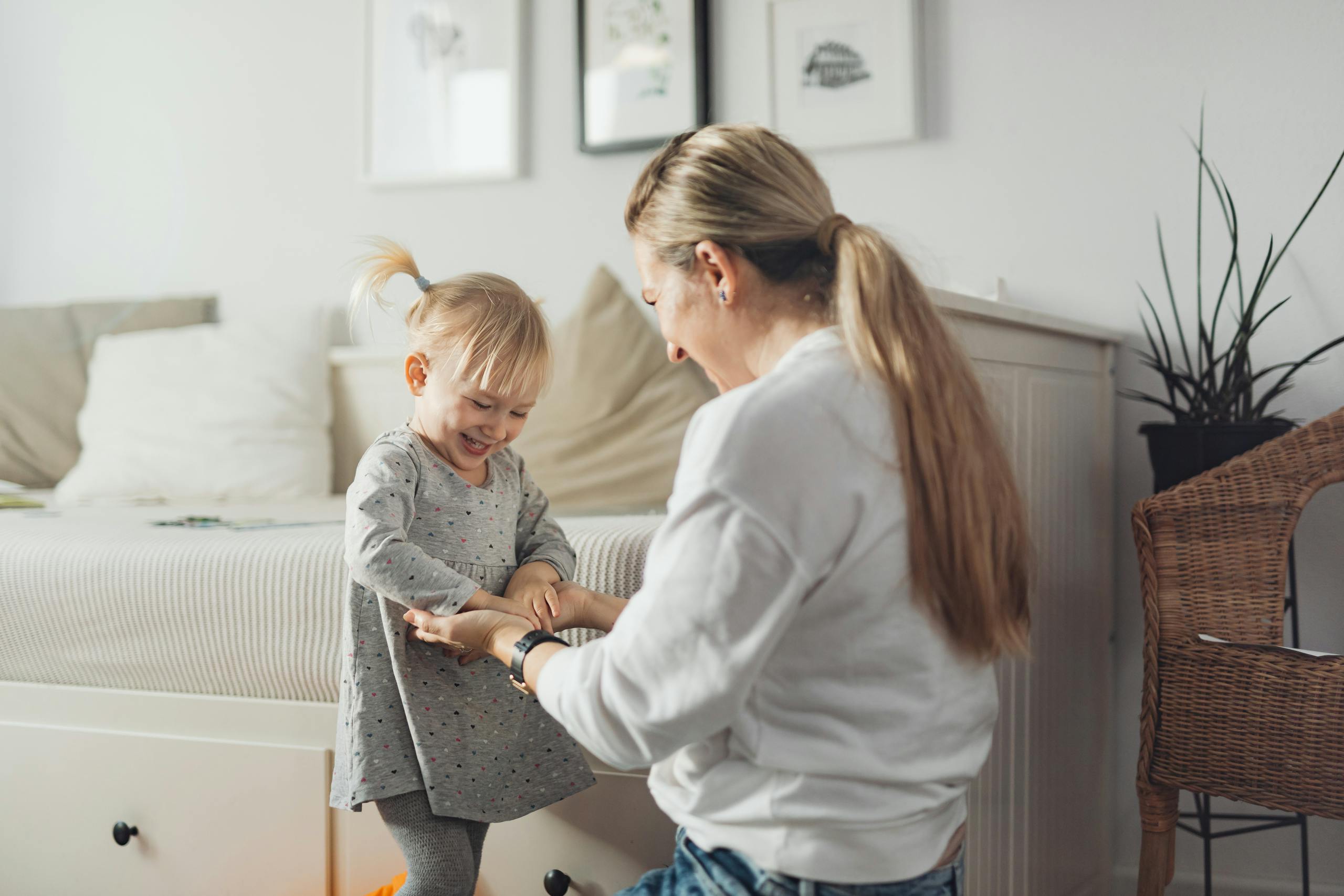 A mother and daughter laughing and playing together inside a cozy home setting.