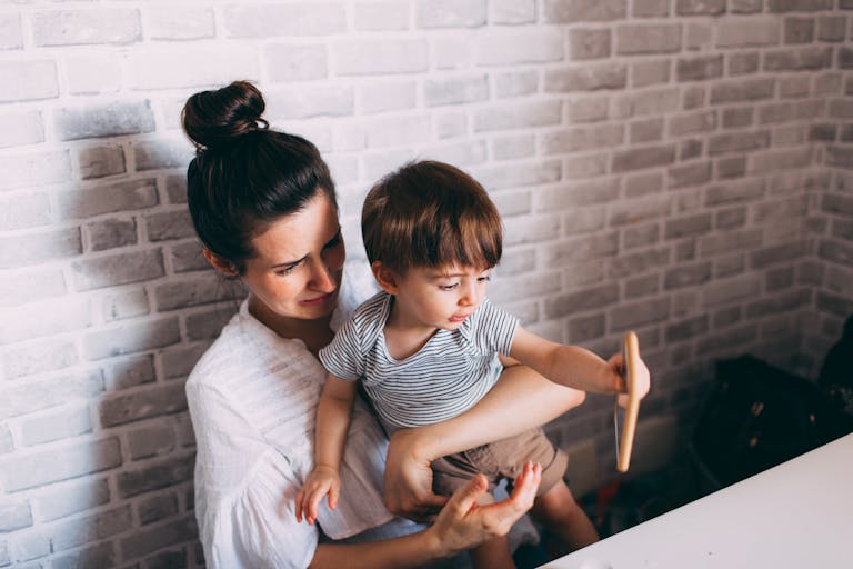 A mother lovingly holds her toddler indoors, sharing a joyful moment together.