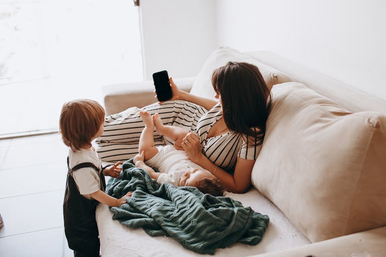 A mother reclines on a sofa with her children, showcasing family leisure time.