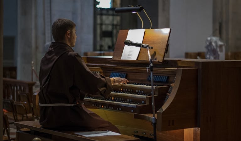 A musician plays a pipe organ in a church setting, adding a serene and classical ambiance.