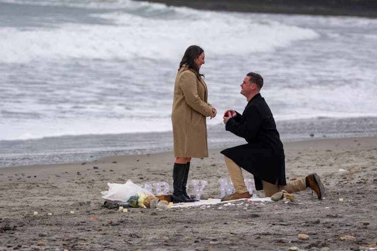 A romantic winter beach proposal in Narragansett, Rhode Island, with a couple embracing love.