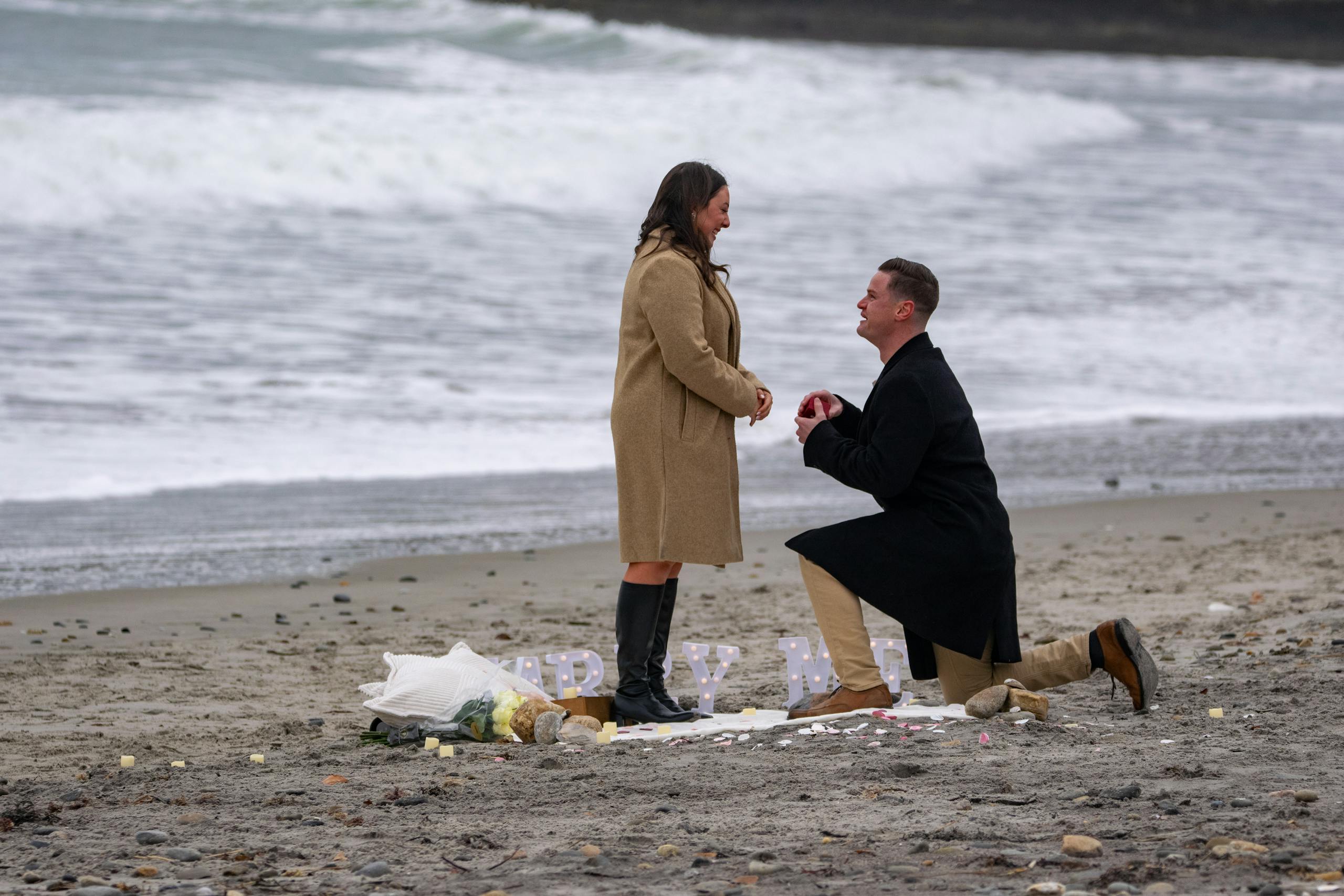 A romantic winter beach proposal in Narragansett, Rhode Island, with a couple embracing love.