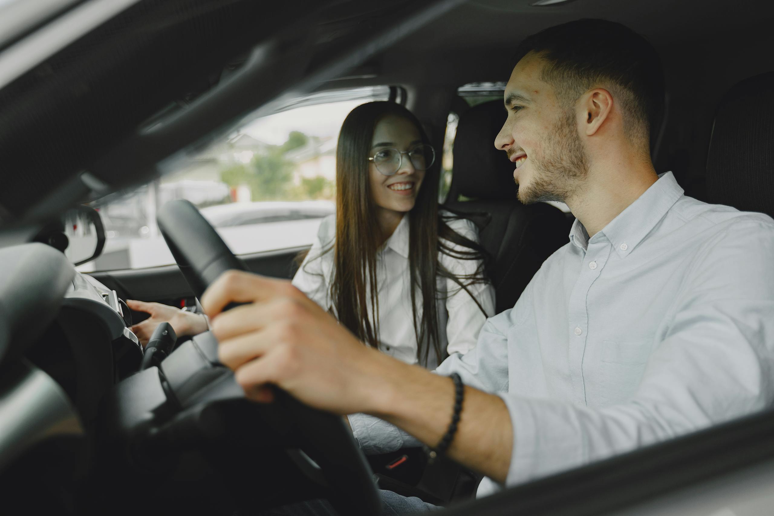 A smiling couple driving together in a car, enjoying their time on the road.
