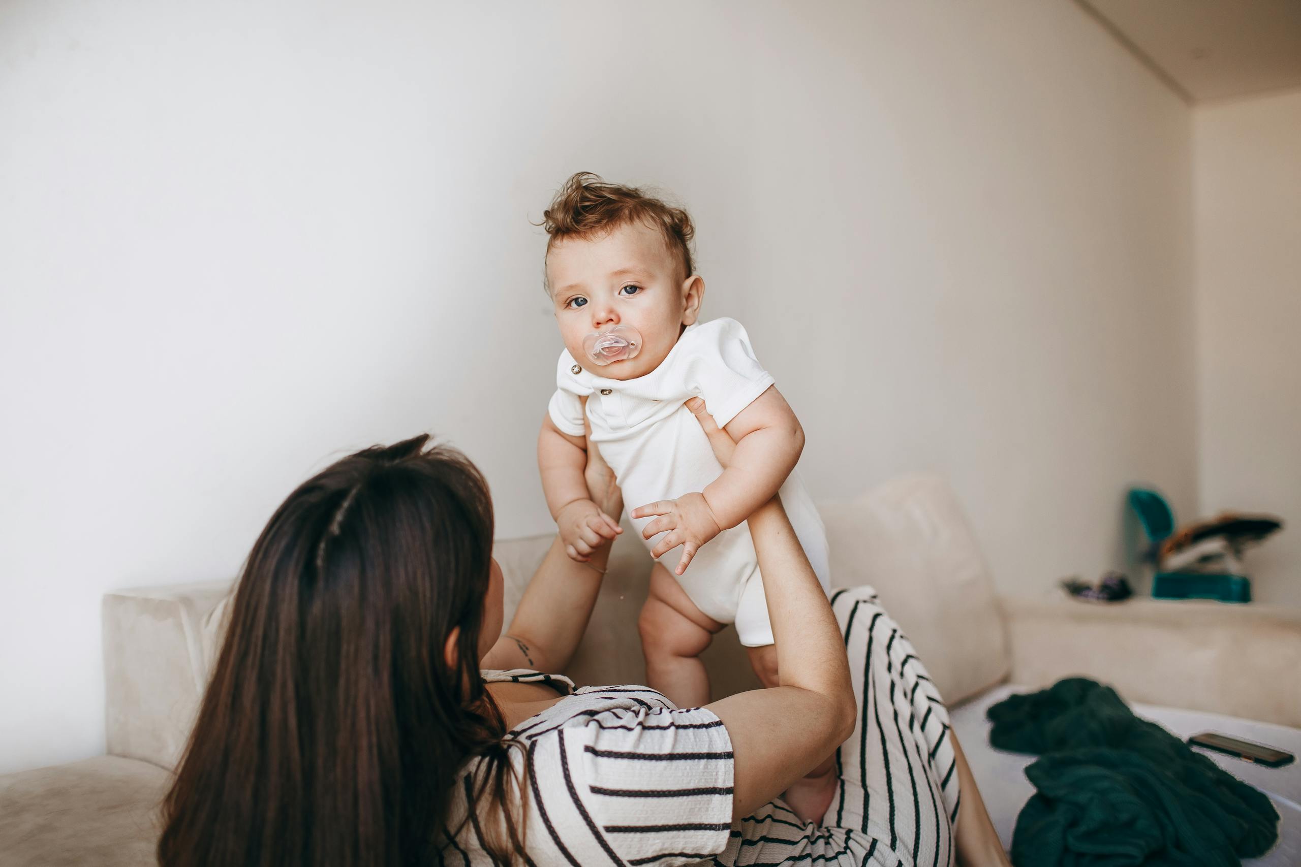 A tender moment of a mother holding her baby in a cozy living room setting.