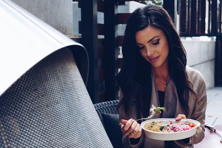 A woman enjoys a nutritious salad in an outdoor setting, capturing a moment of healthy lifestyle.