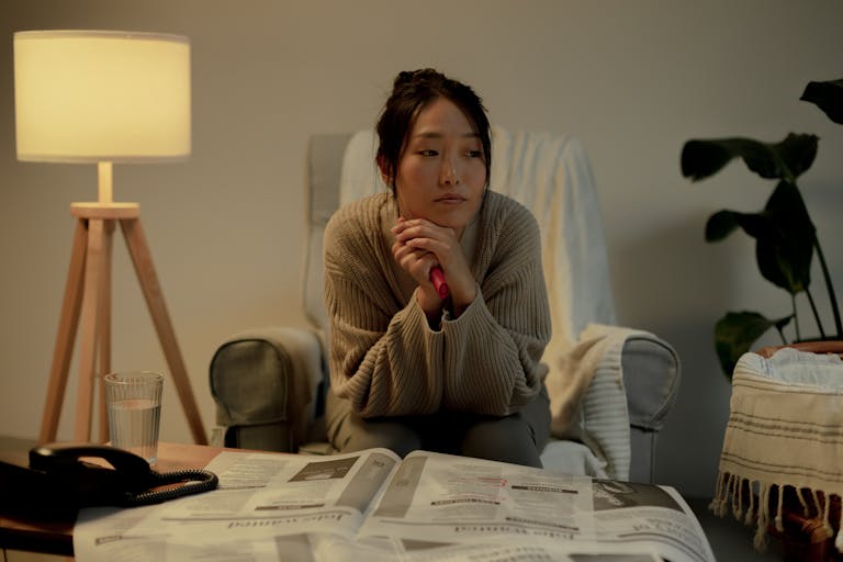 A woman in an armchair, contemplating job search in a cozy living room.