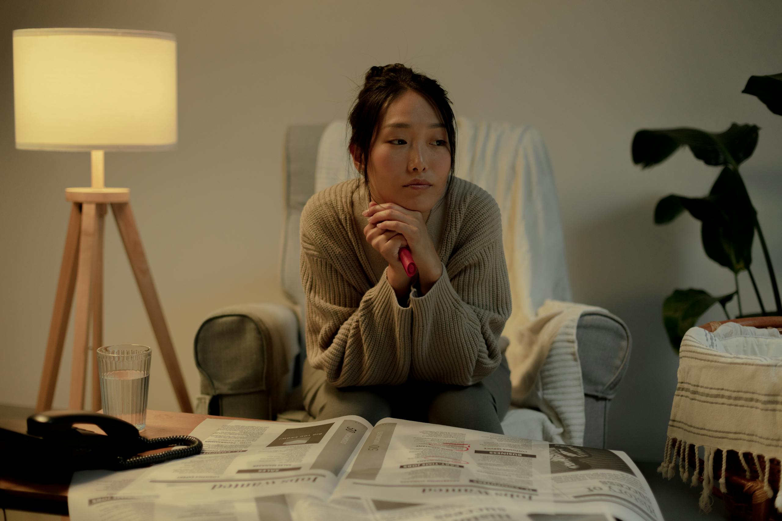 A woman in an armchair, contemplating job search in a cozy living room.