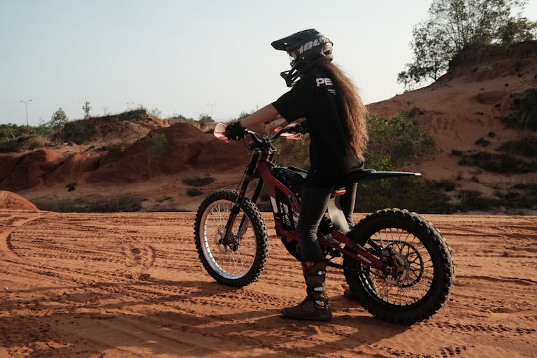 A woman on a dirt bike rides through a sandy desert, enjoying off-road adventure.