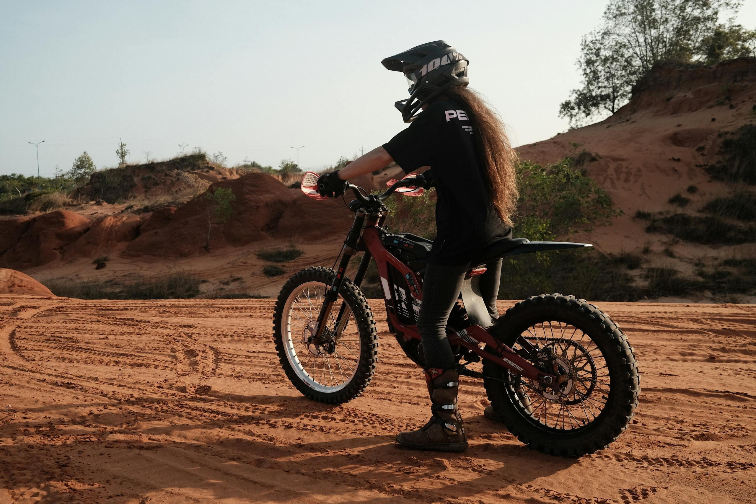 A woman on a dirt bike rides through a sandy desert, enjoying off-road adventure.