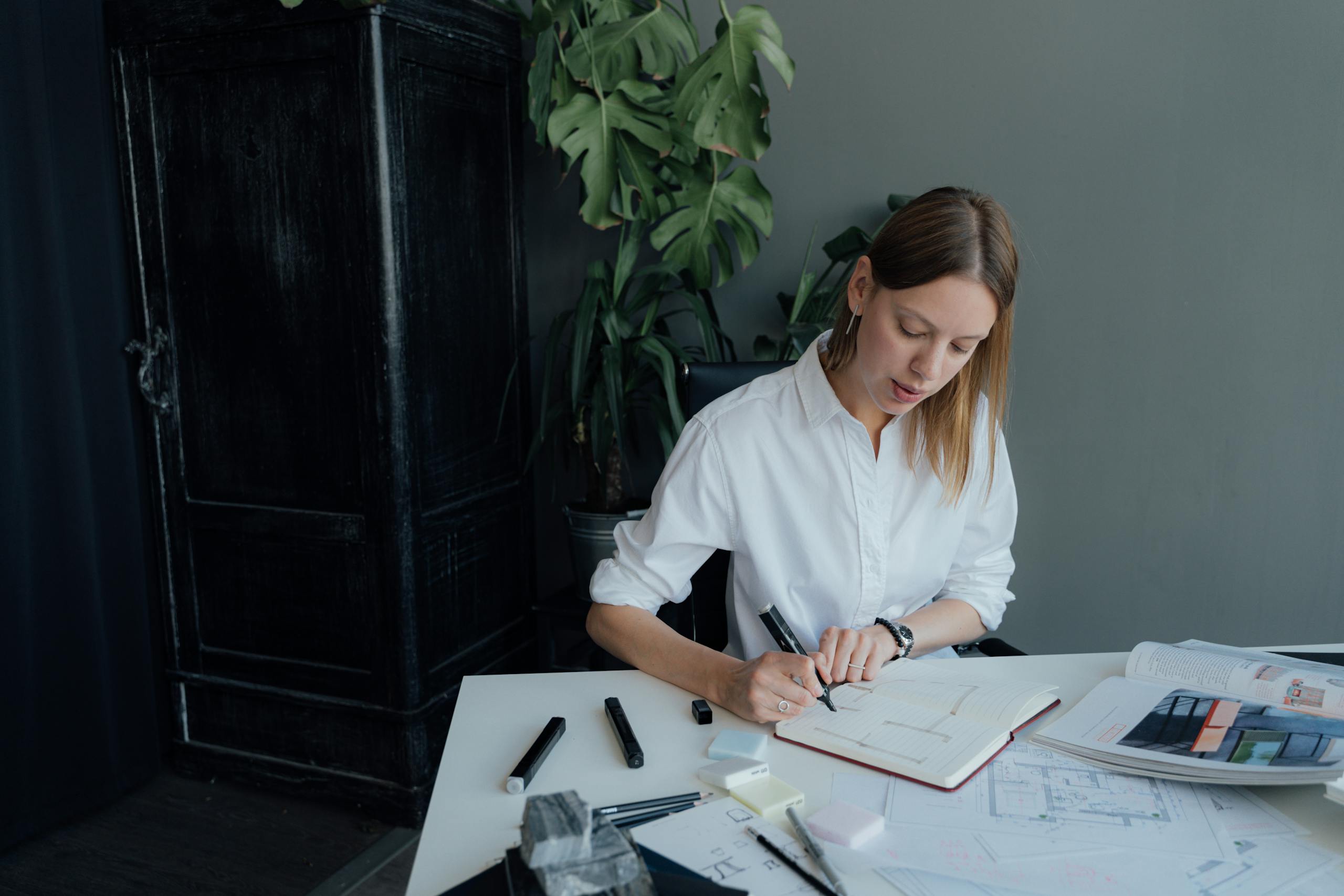A young female architect working on floor plans at home, blending creativity and professionalism.