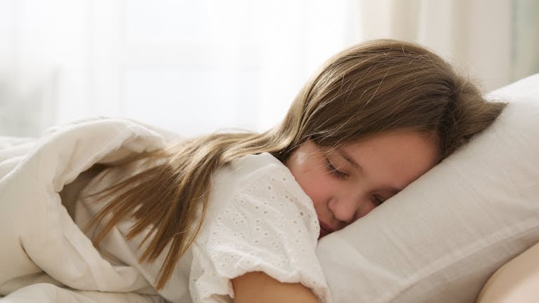 A young girl peacefully sleeping on a pillow, enveloped in soft light and comfort.