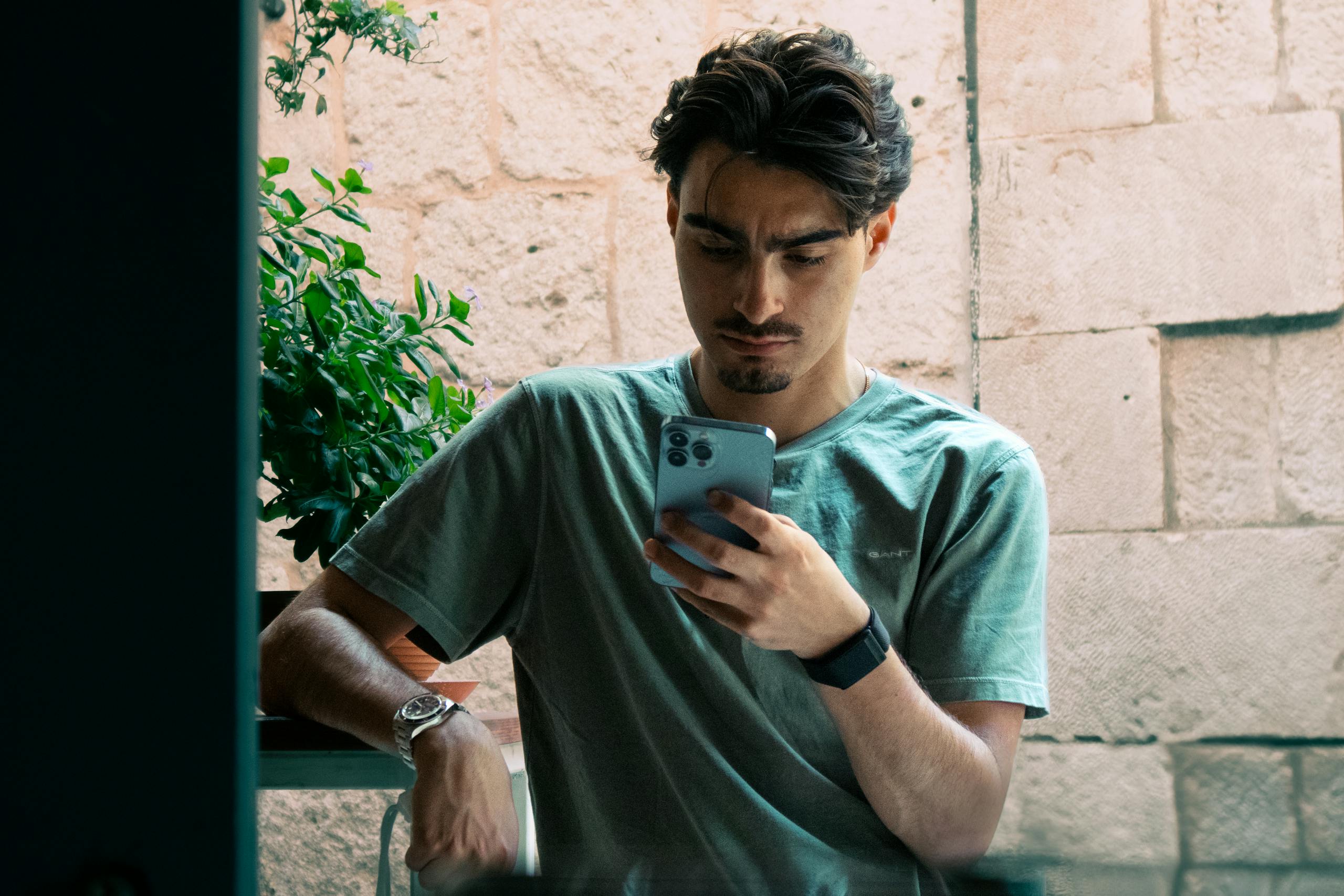 A young man in casual attire checking his phone outside in Split, Croatia.