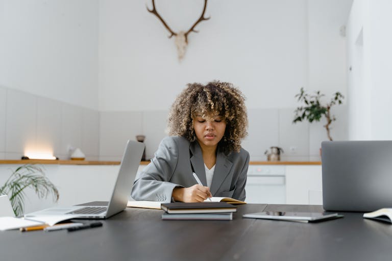 African American woman writing in a planner at a stylish office desk.
