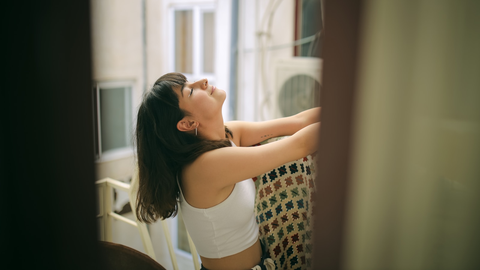 A woman in a white top is leaning on a window sill