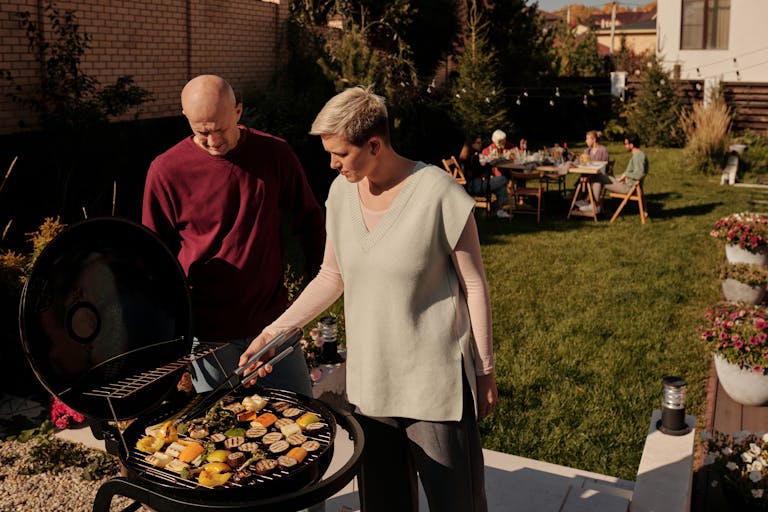 Couple grilling vegetables at a backyard barbecue gathering.