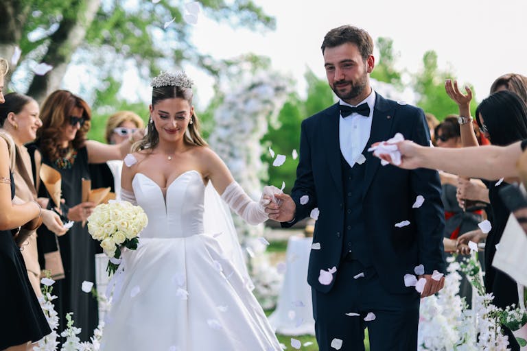 Couple joyfully exits wedding ceremony amidst confetti showers and guests' applause.
