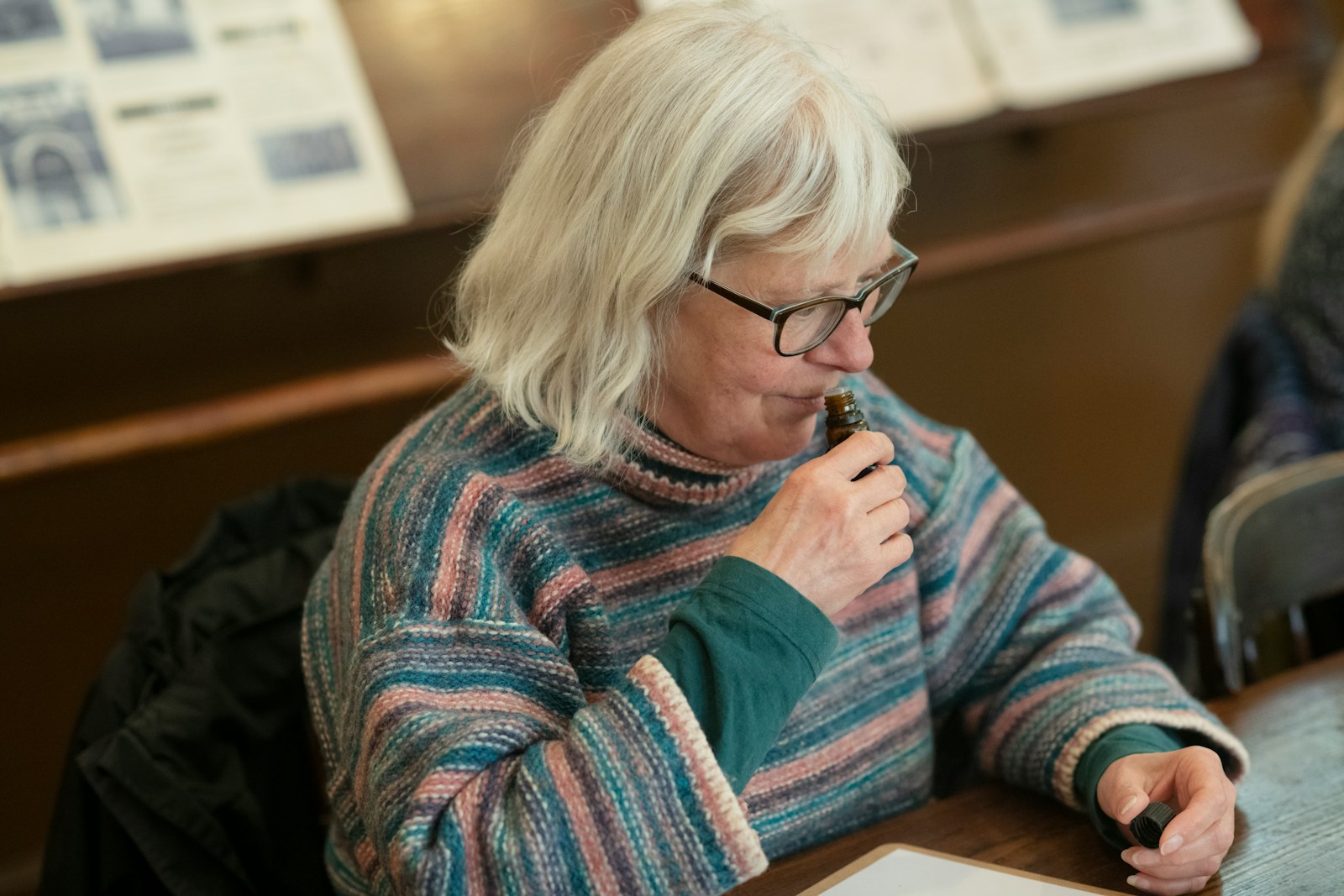 a woman sitting at a table with a pen in her mouth