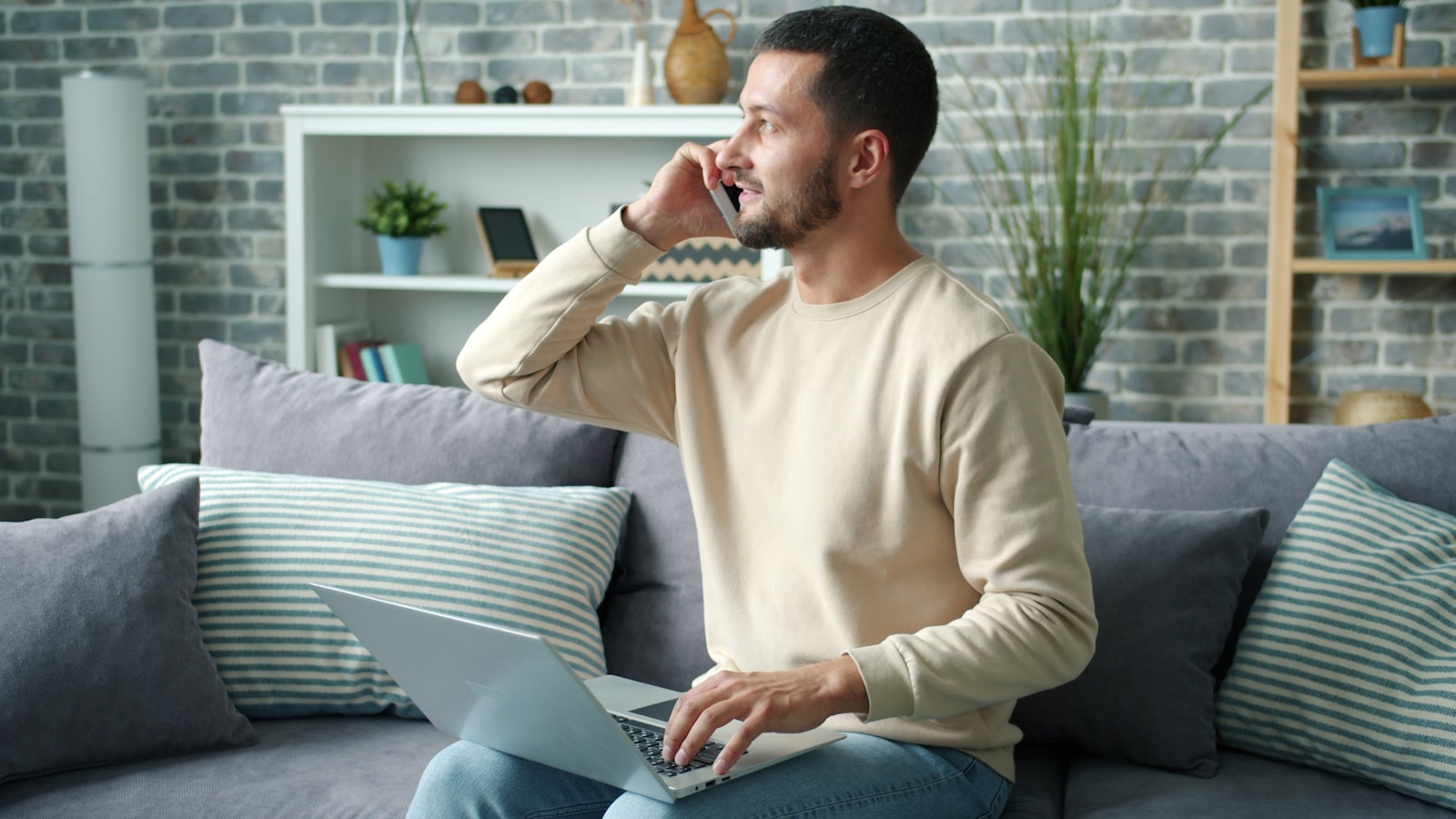 Man talking on phone with laptop on lap