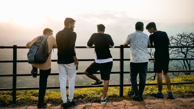 Group of young men enjoying a sunset view from a hilltop in India.