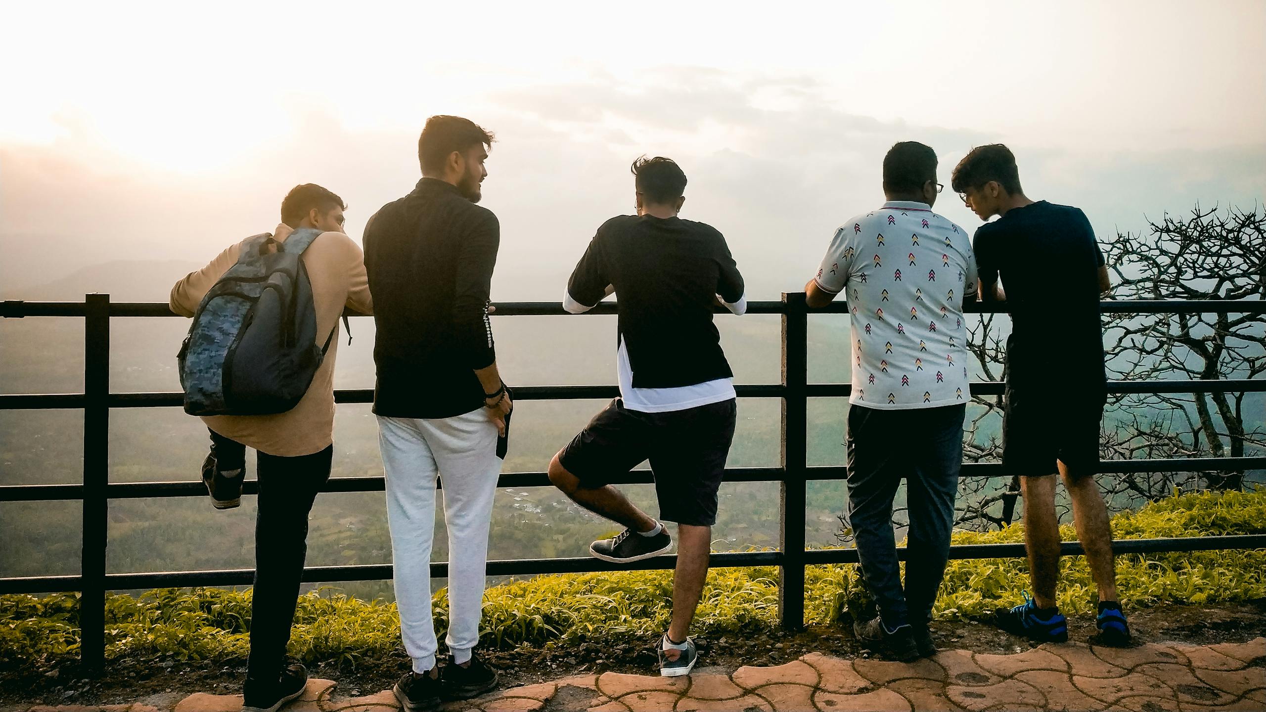 Group of young men enjoying a sunset view from a hilltop in India.