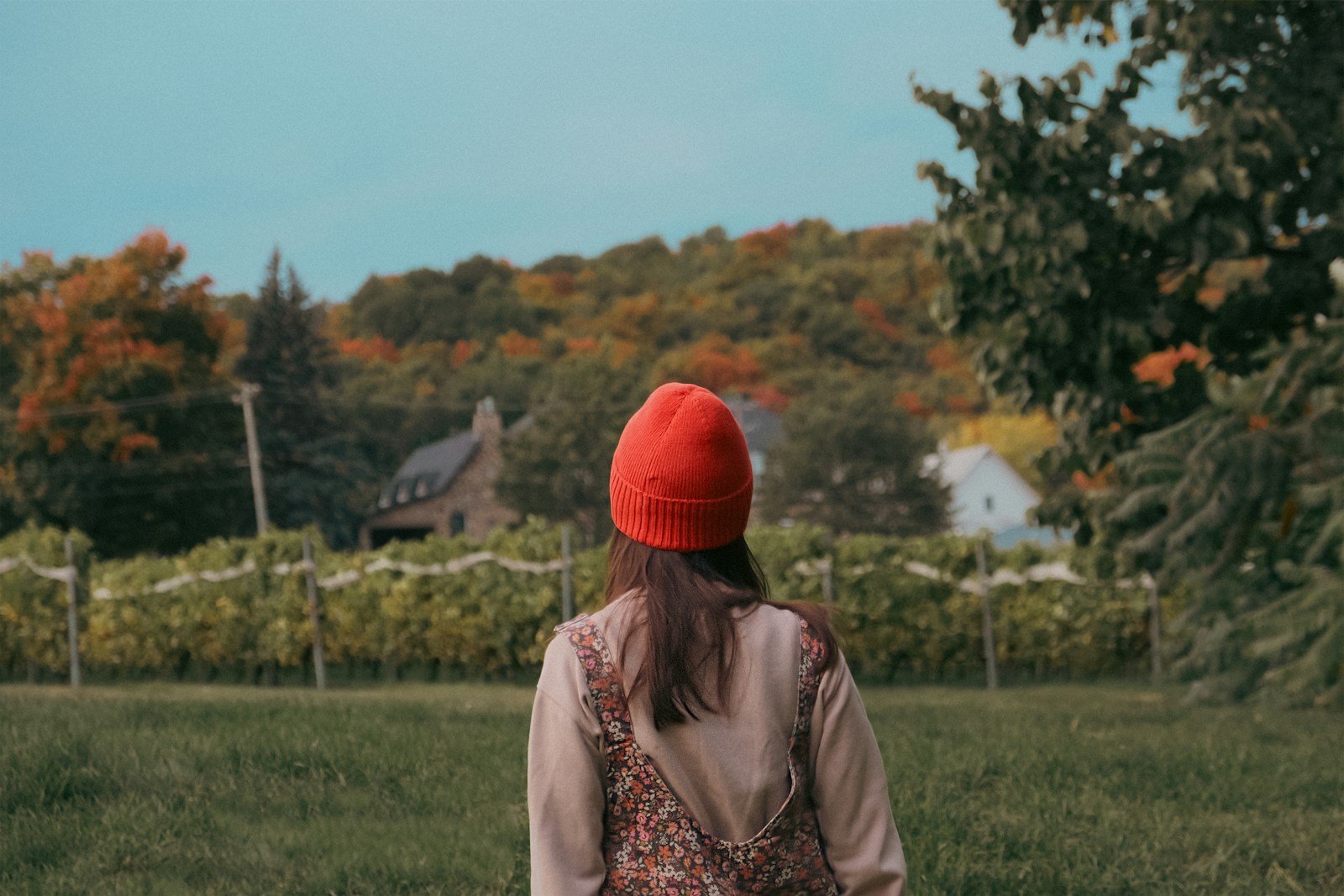 A woman in a red hat walking through a field