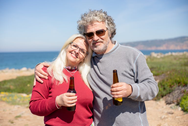 Happy couple drinking beer together on a sunny day by the ocean in Portugal.