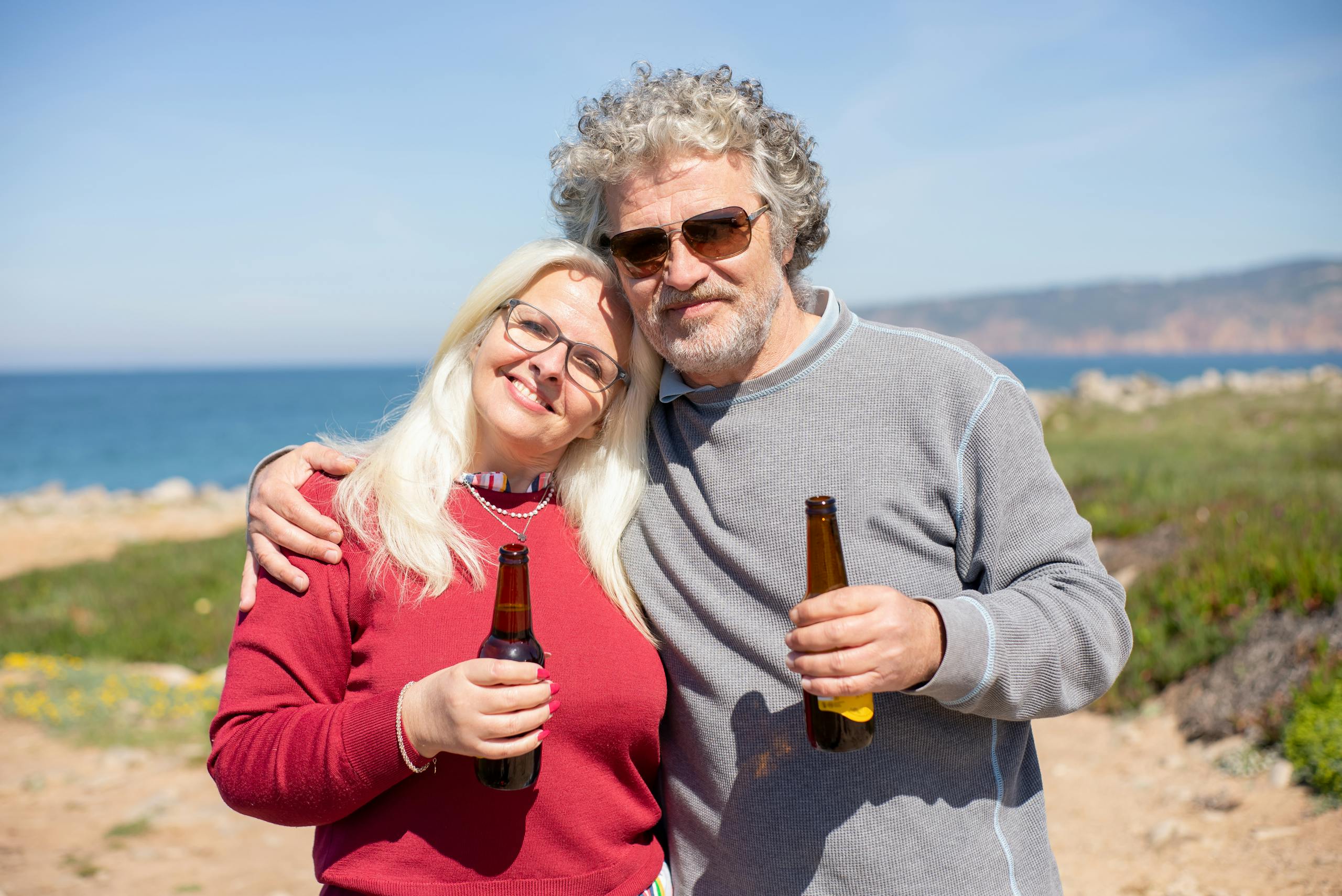 Happy couple drinking beer together on a sunny day by the ocean in Portugal.