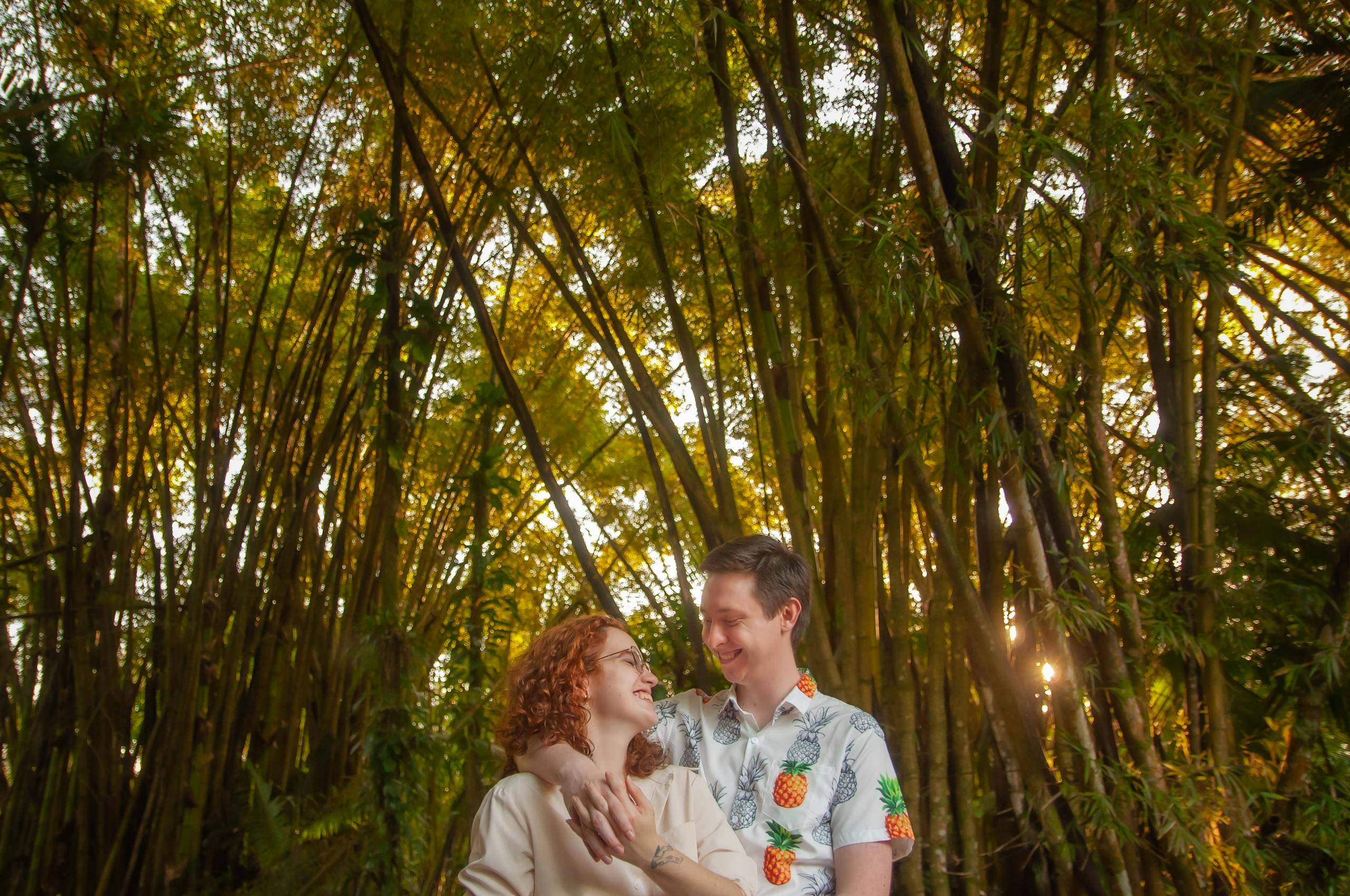 Happy couple embracing in a serene bamboo forest, basking in sunlight.
