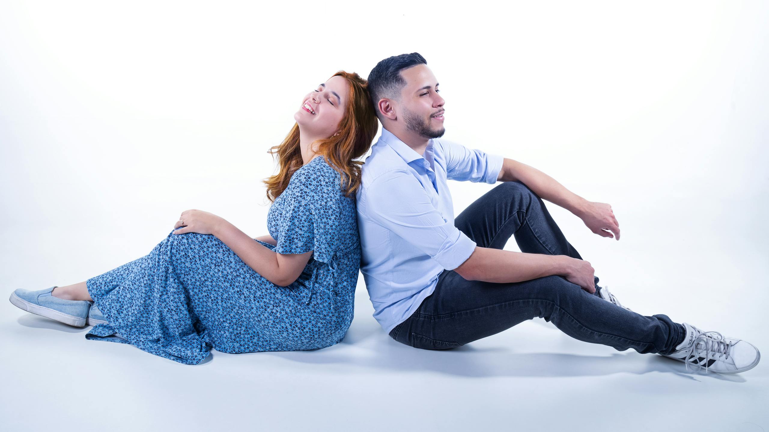 Happy couple sitting back to back in a studio, embracing togetherness and joy.