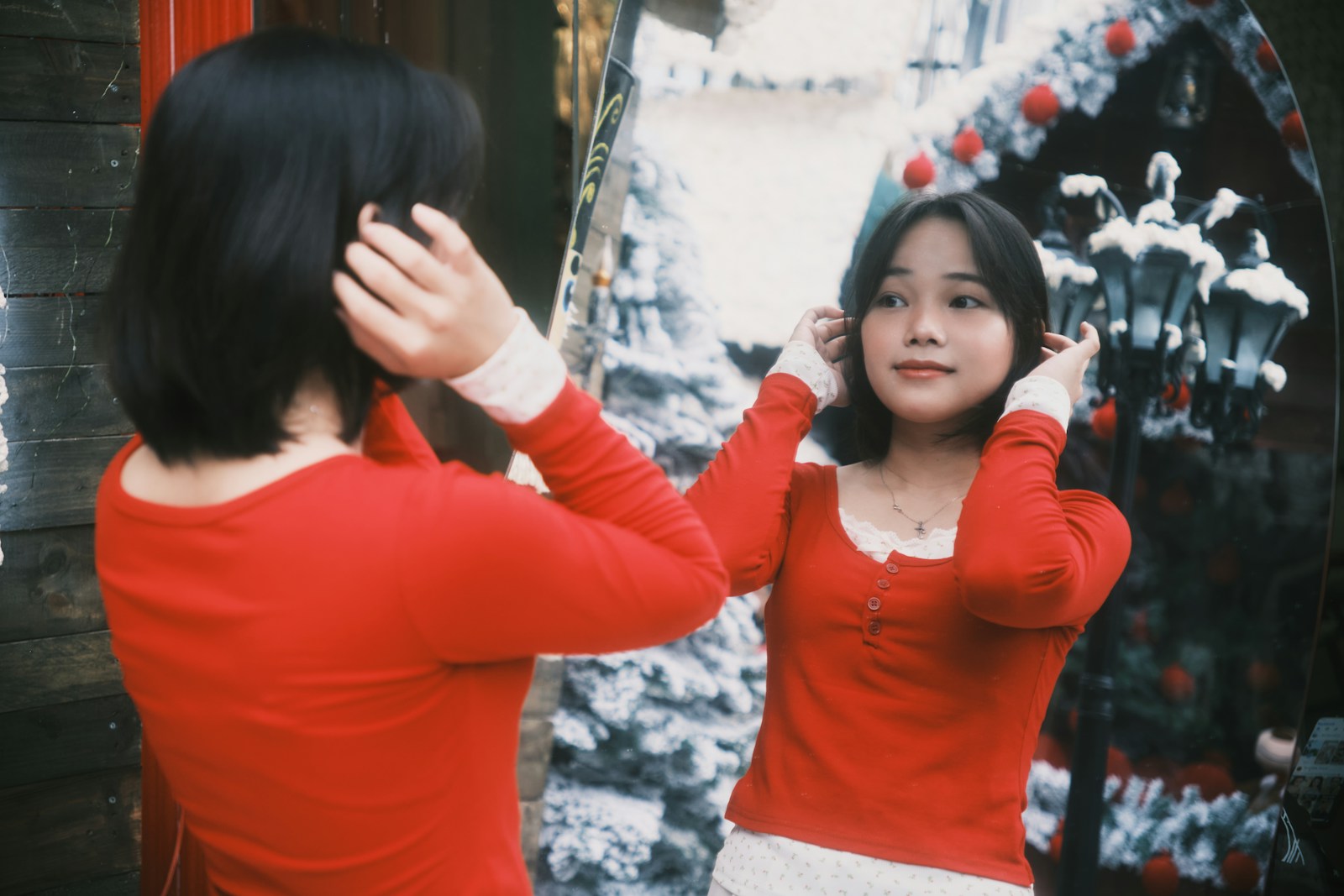 Young woman in red shirt looks in mirror
