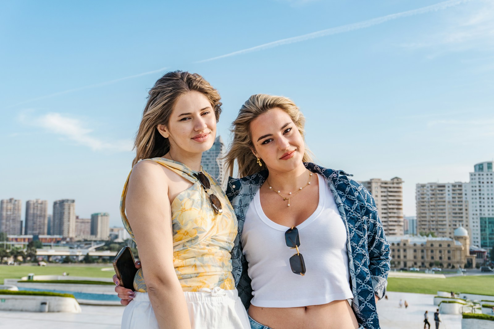 Two women posing with city buildings in the background.