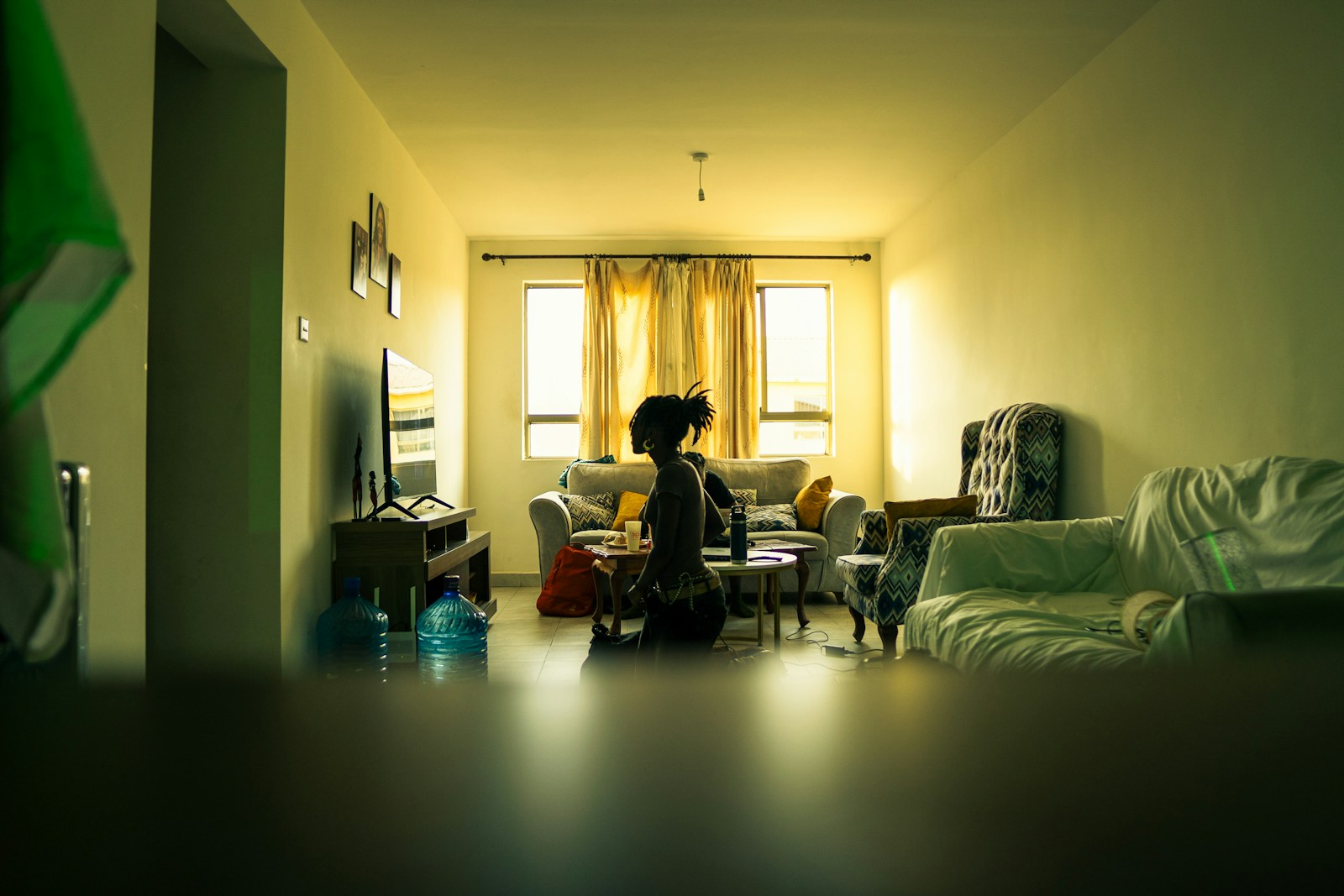 A person kneels in a dimly lit living room.