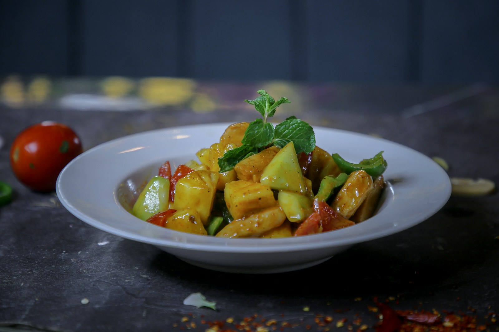 A fruit salad with mint garnish in a white bowl.