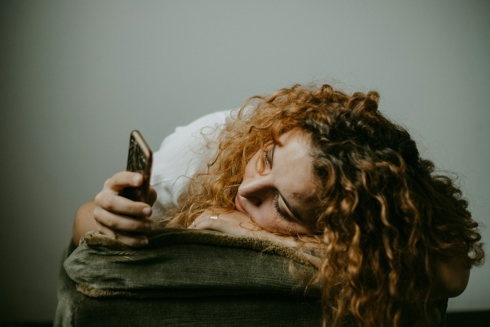 woman in gray sweater holding smartphone
