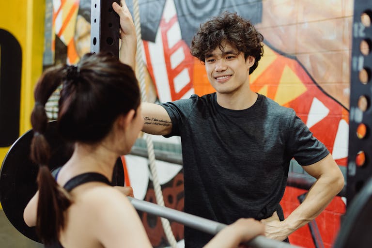 Man and woman engage in a friendly conversation in a gym with colorful graffiti walls.