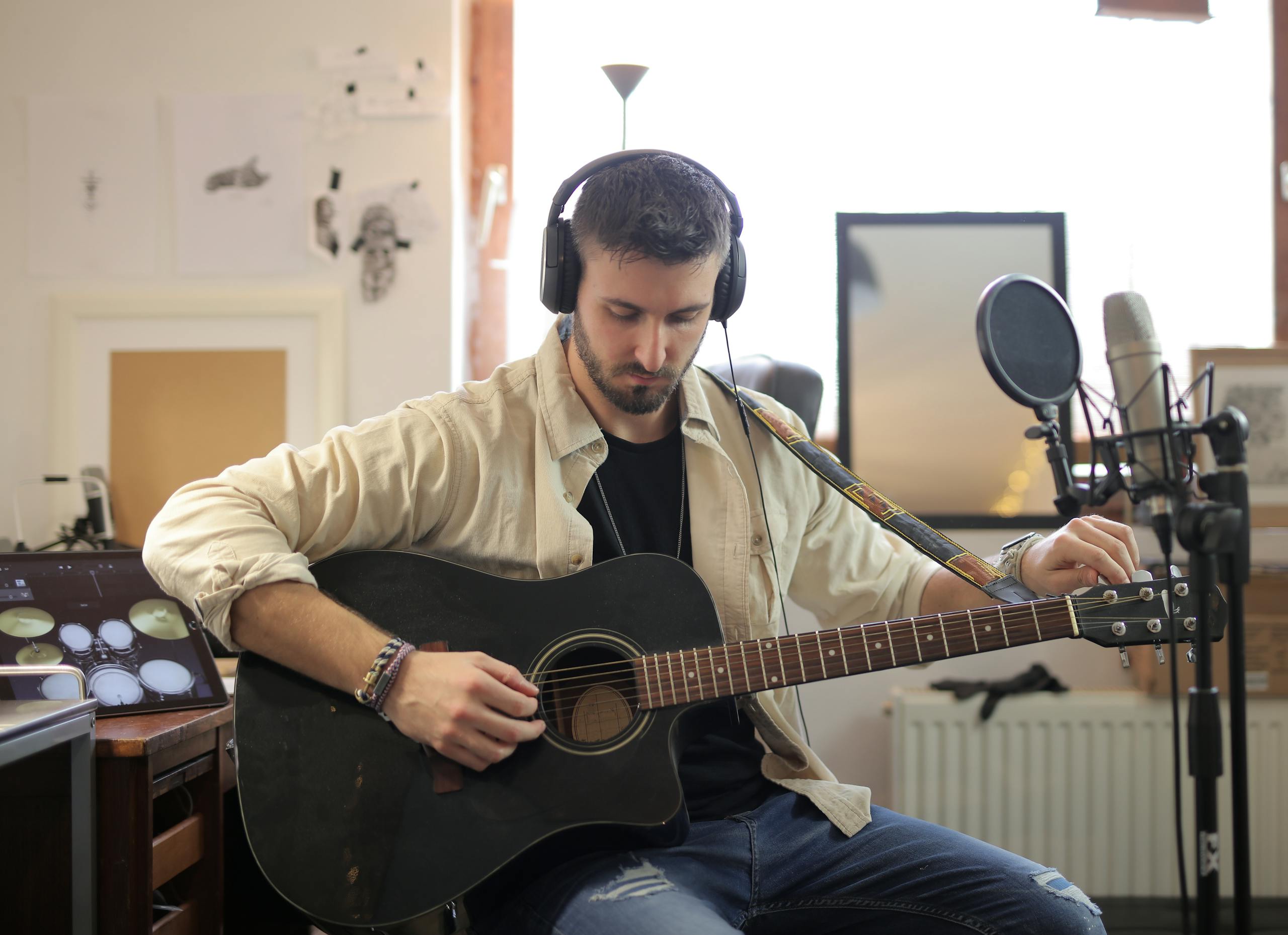 Musician adjusting guitar strings in modern recording studio environment.