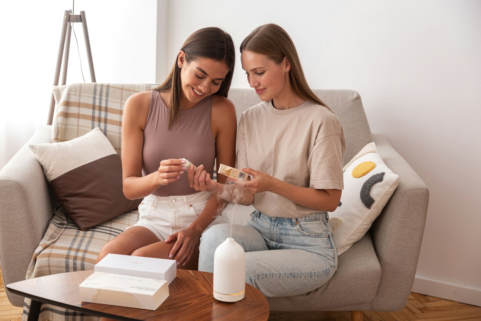 two women sitting on a couch looking at a cell phone