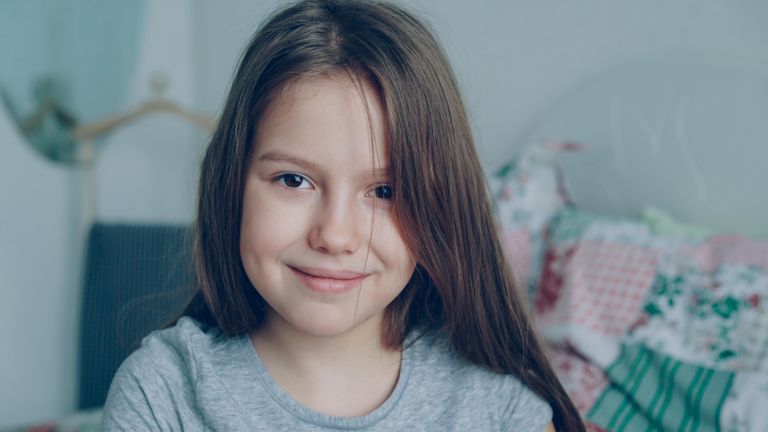 Portrait of a smiling young girl indoors with long hair and soft lighting.