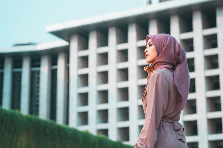 Profile of a woman in a hijab with Istiqlal Mosque in the background, Jakarta.