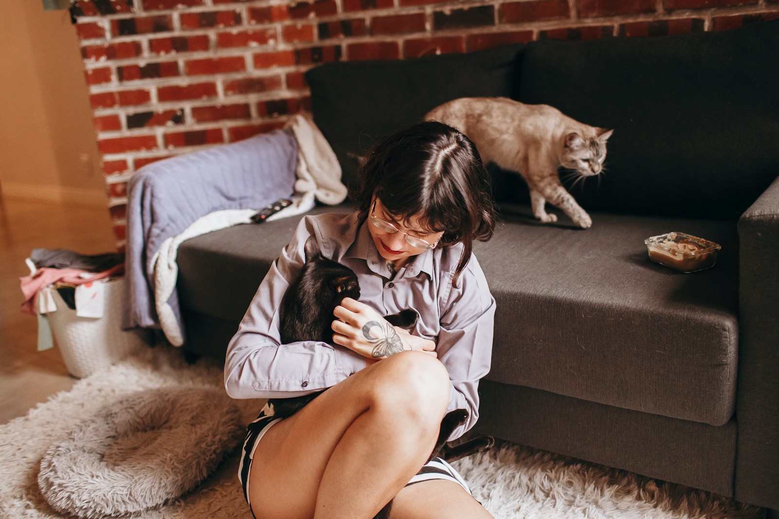 woman in pink jacket sitting on gray couch